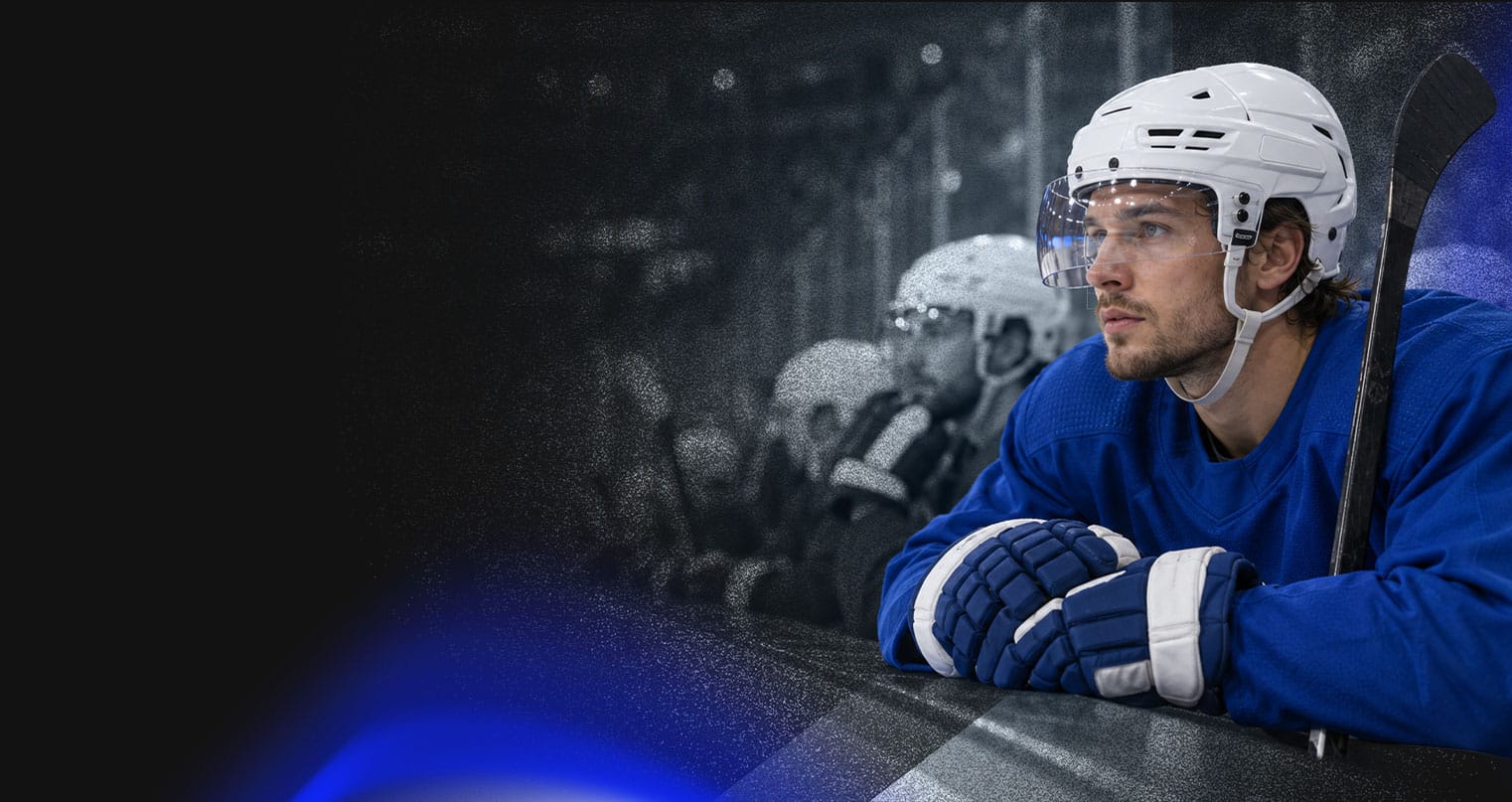 NHL player leaning on the boards at the bench during a game.
